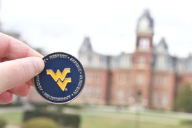 Blue and gold front of WVU Values coin, flying WV in the middle with the values of service curiosity respect accountability and appreciation surrounding. 