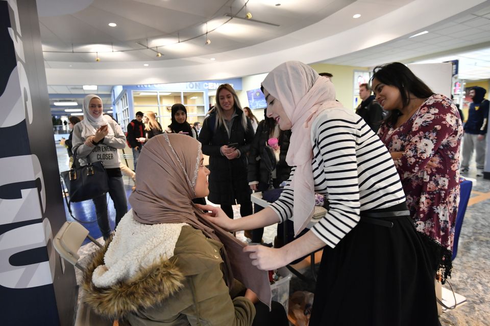 WVU Muslim Students Association member helps a student put on a hijab