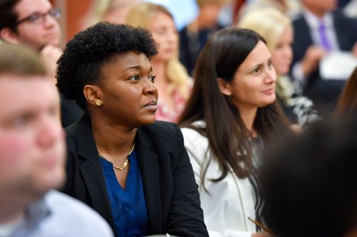 two women sitting in an audience listening to a speaker