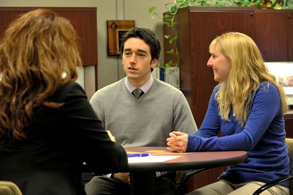 Three WVU Employees conversing around a table 